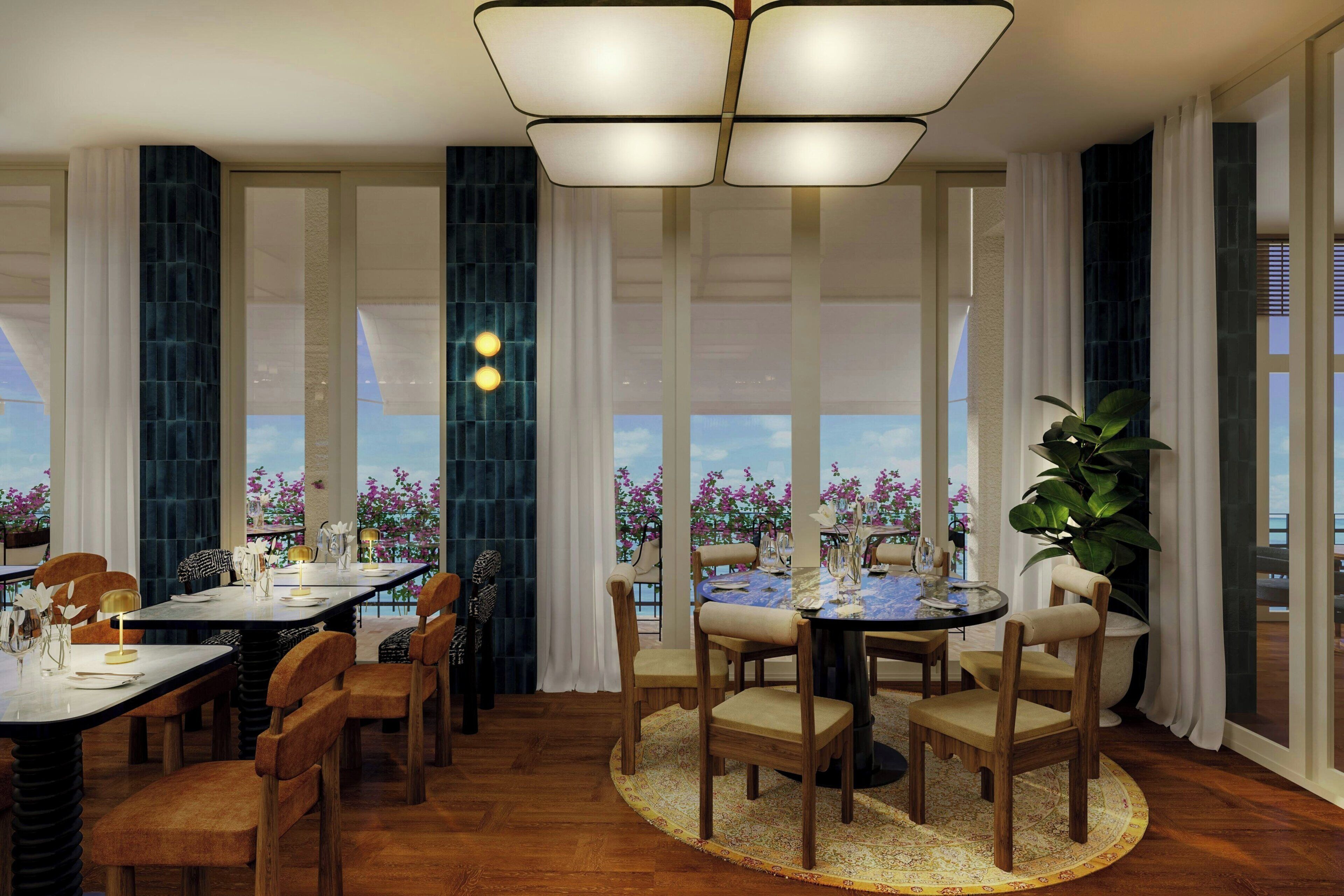 Un comedor con una mesa redonda, sillas y vistas a flores a través de las ventanas.