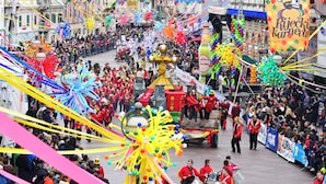 A crowded street parade with colorful decorations and a crowd of people.