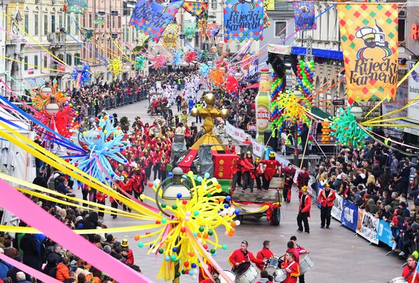 A crowded street parade with colorful decorations and a crowd of people.