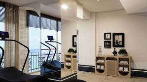 Une salle de sport équipée de matériel d’exercice, un comptoir d’accueil et une vue sur la mer.