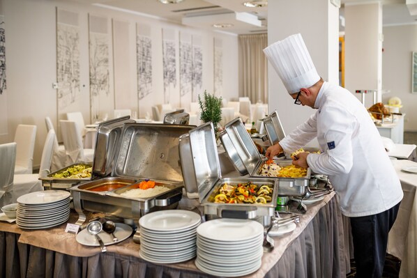 A buffet setup with multiple food stations, including rice, vegetables, and pasta.