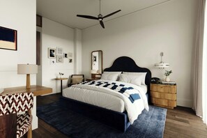 A bedroom with a bed, bedside tables, a mirror, a ceiling fan, and artwork on the wall.