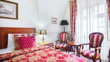 Une chambre d’hôtel avec un grand lit, une table de chevet en bois, une chaise, une petite table et une lampe.
