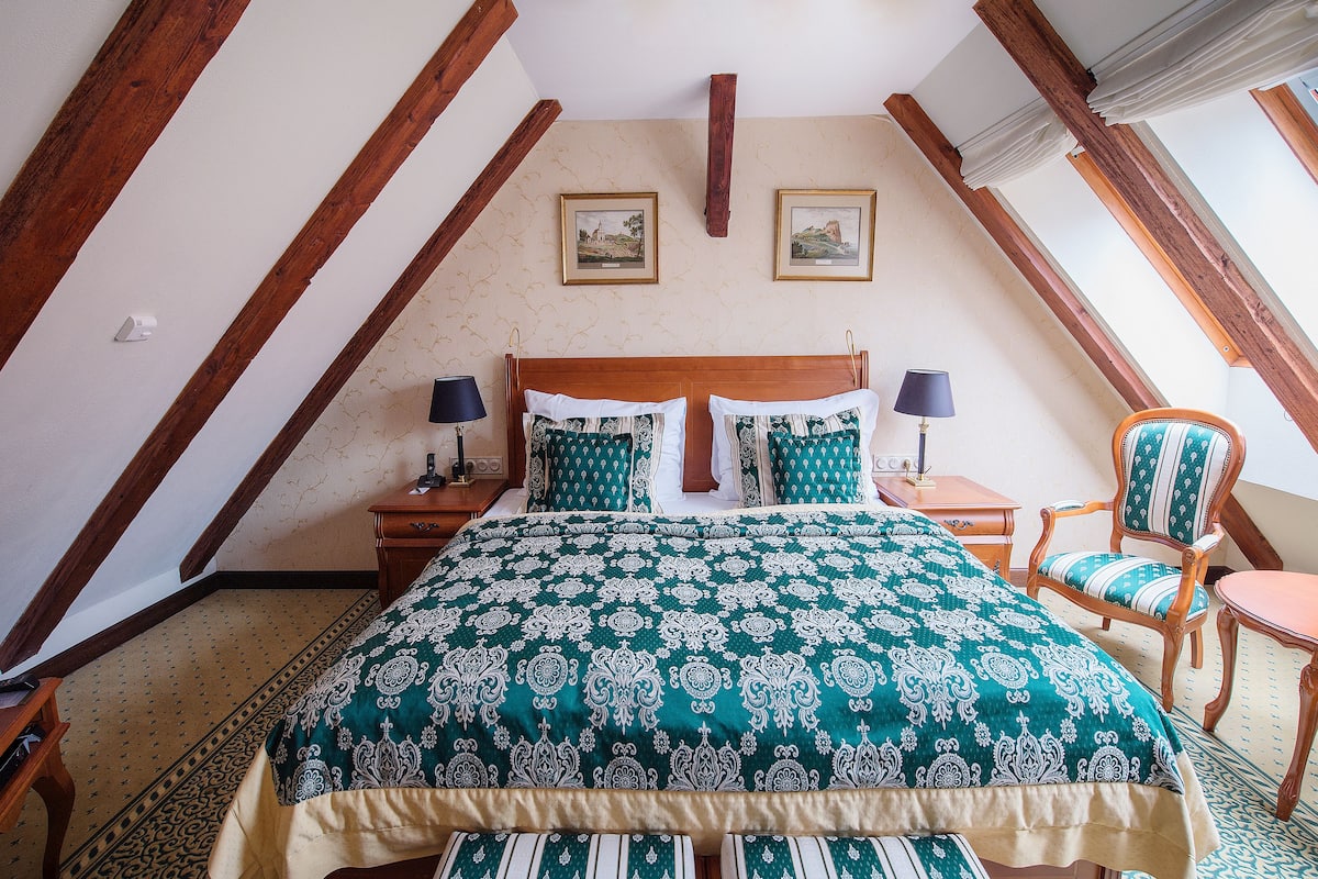 Ein Schlafzimmer mit einem großen Bett, zwei Nachttischen, einem Sessel und einem kleinen Tisch.