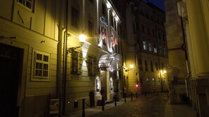 Un edificio histórico con una entrada destacada, una zona cubierta con techo metálico y una señal de tráfico que indica un parada.