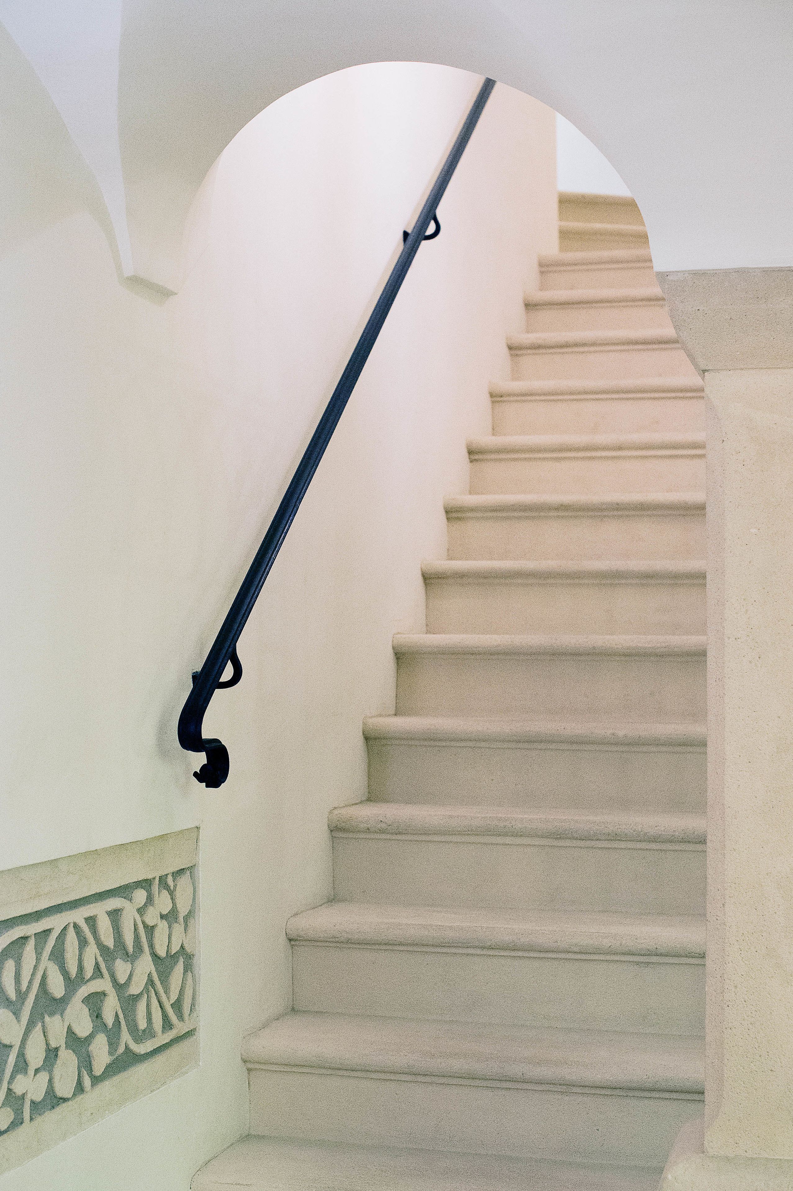 A staircase with beige steps and a black handrail, leading to an upper level.