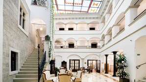 Un vestíbulo amplio con una escalera central, varias zonas de estar y un techo alto con tragaluces.