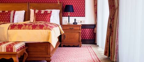 A hotel room with a large bed, a nightstand with a lamp, and a wooden dresser.
