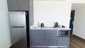 A compact kitchen with a built-in refrigerator, a microwave, and a sink. - Marjac Suites Virginia Beach Oceanfront (Virginia Beach)