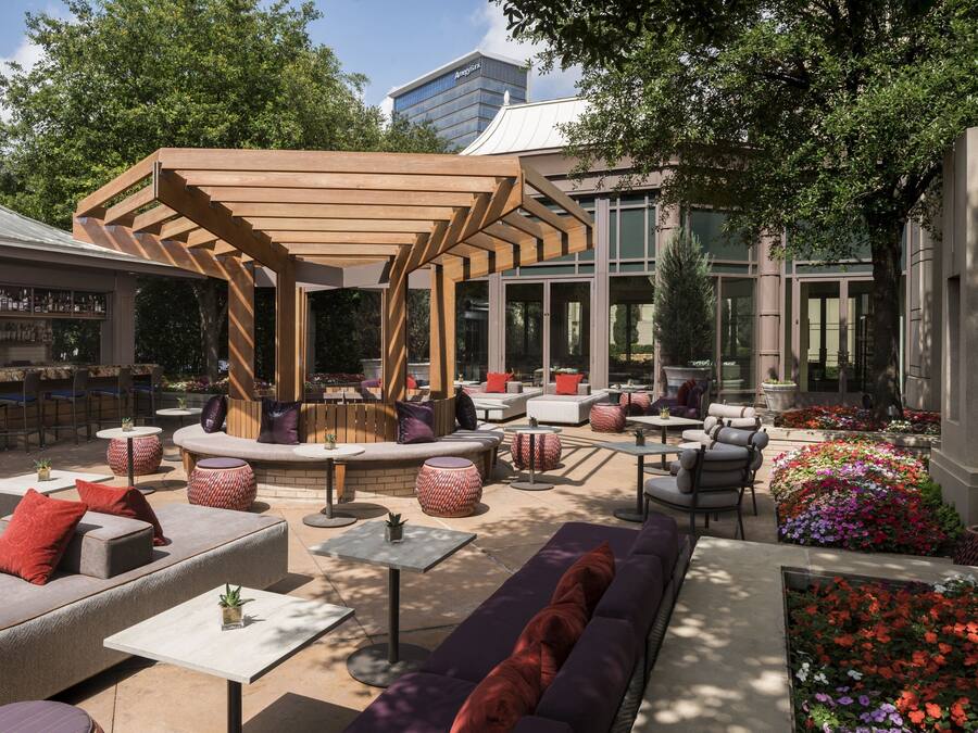Un espace extérieur aménagé avec des canapés, des tables et une structure de pergola en bois.