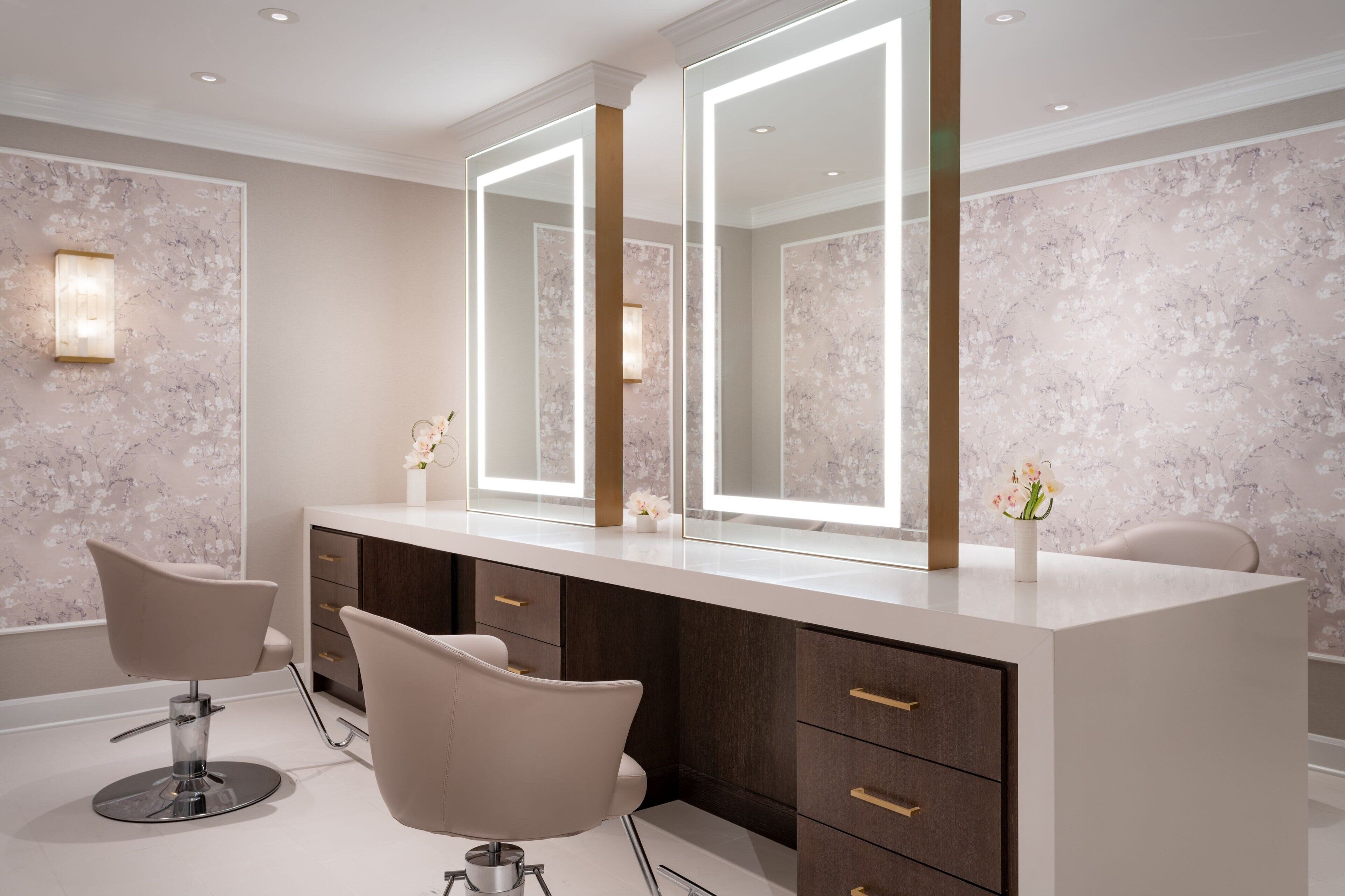A modern bathroom with a large mirror, two chairs, and a vanity with drawers.