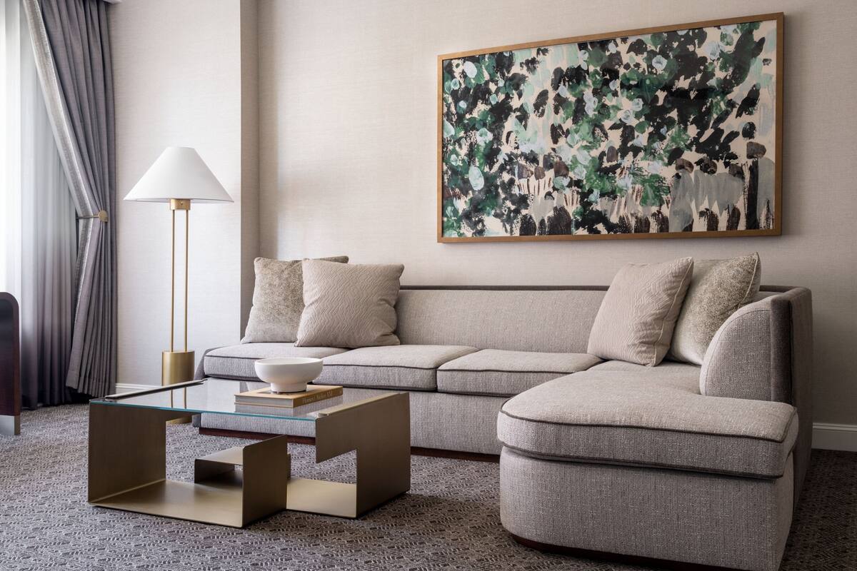 A modern living room with a beige sofa, a glass coffee table, and a floor lamp.