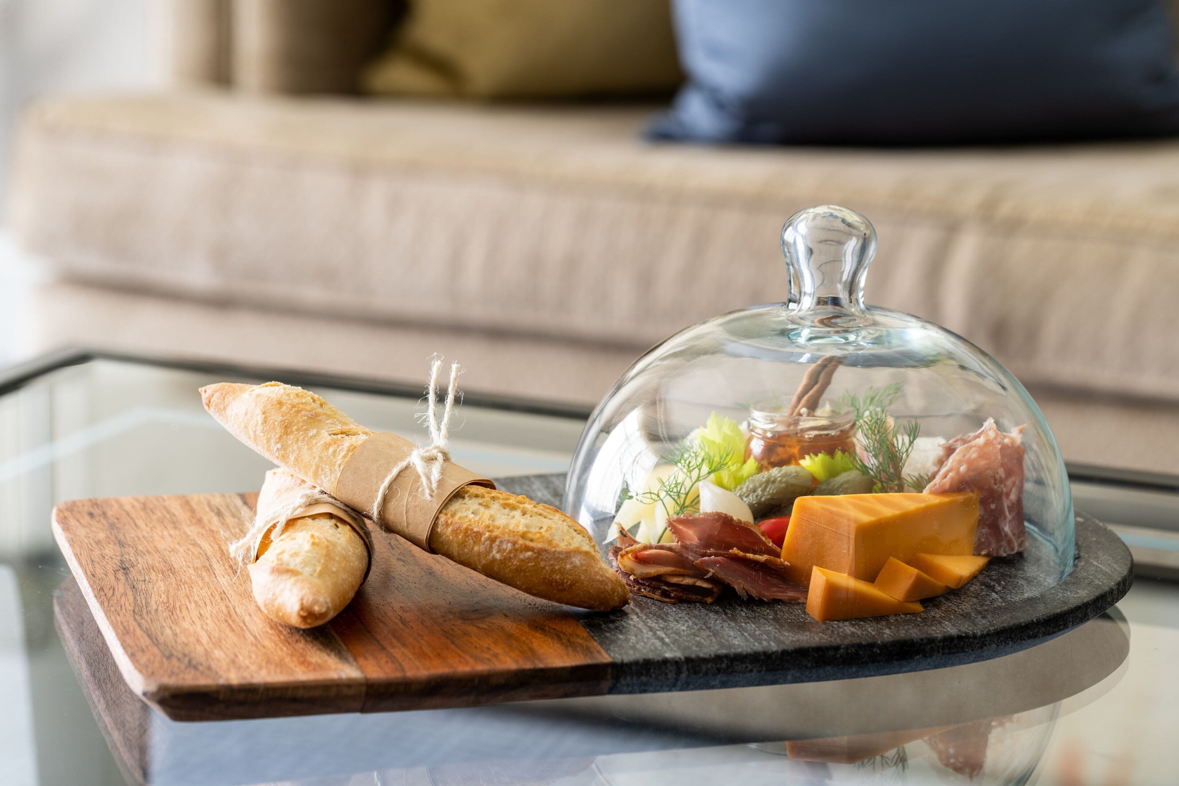 Un expositor de vidrio con diversos quesos y embutidos sobre una mesa de cristal.