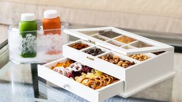 A tray with ice and two bottles, a white box with compartments containing various snacks and dried fruits.