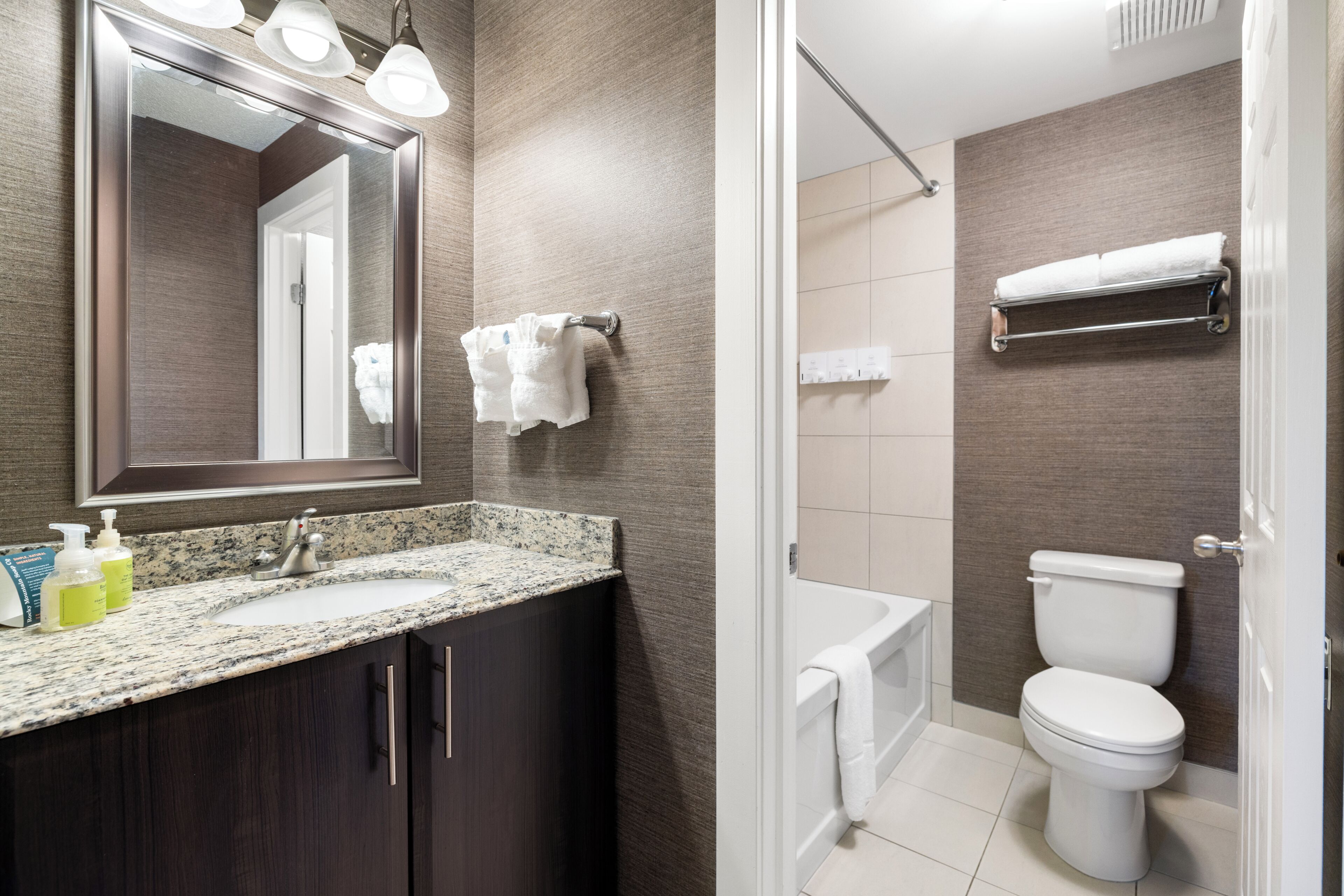 A bathroom with a sink, mirror, towel rack, and toilet.