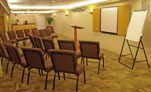A conference room with rows of brown chairs, a whiteboard, and a projector screen. - Irwin's Mountain Inn (Banff)