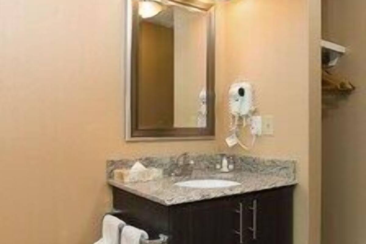 A bathroom with a dark vanity, a mirror, and a towel rack.