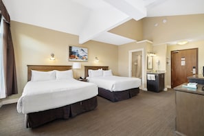 A hotel room with two beds, a bathroom, and a desk with a mirror. - Irwin's Mountain Inn (Banff)