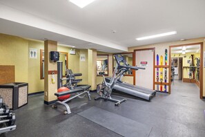 A gym with exercise equipment, a treadmill, and a wall-mounted ski rack.