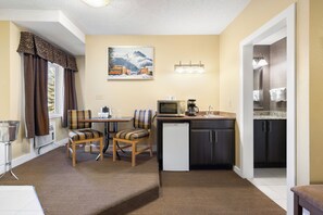 A compact kitchen with a dining area, a refrigerator, and a microwave. - Irwin's Mountain Inn (Banff)