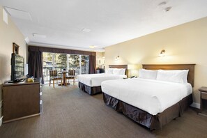 A hotel room with two beds, a desk, and a television.