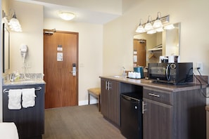 A hotel bathroom with a sink, mirror, hair dryer, and a microwave. - Irwin's Mountain Inn (Banff)