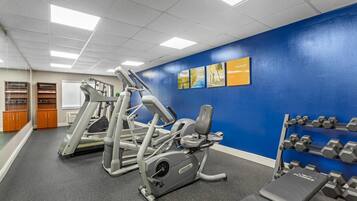 Une salle de sport équipée de machines d’exercice, d’un banc et d’haltères.