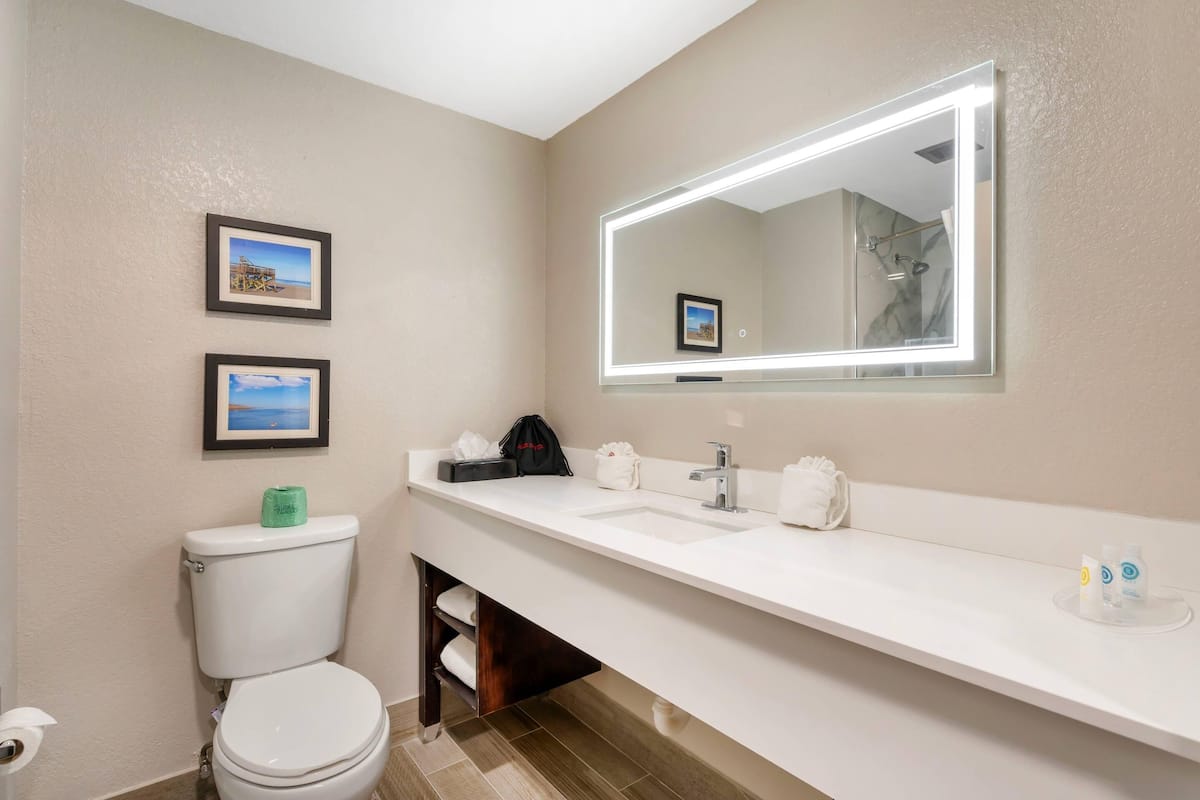 Un baño moderno con un lavamanos, espejo y retrete blancos.