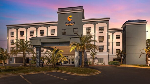 A hotel with a modern design, featuring a prominent logo and multiple balconies. - Comfort Suites West Jacksonville (Jacksonville)