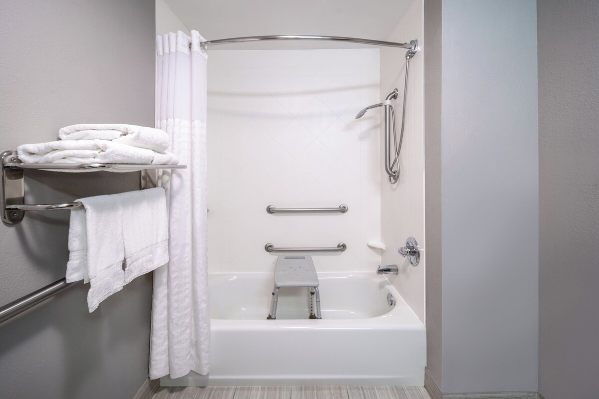 Ein modernes Badezimmer mit barrierefreier Dusche, Haltegriffen und einem Handtuchhalter.