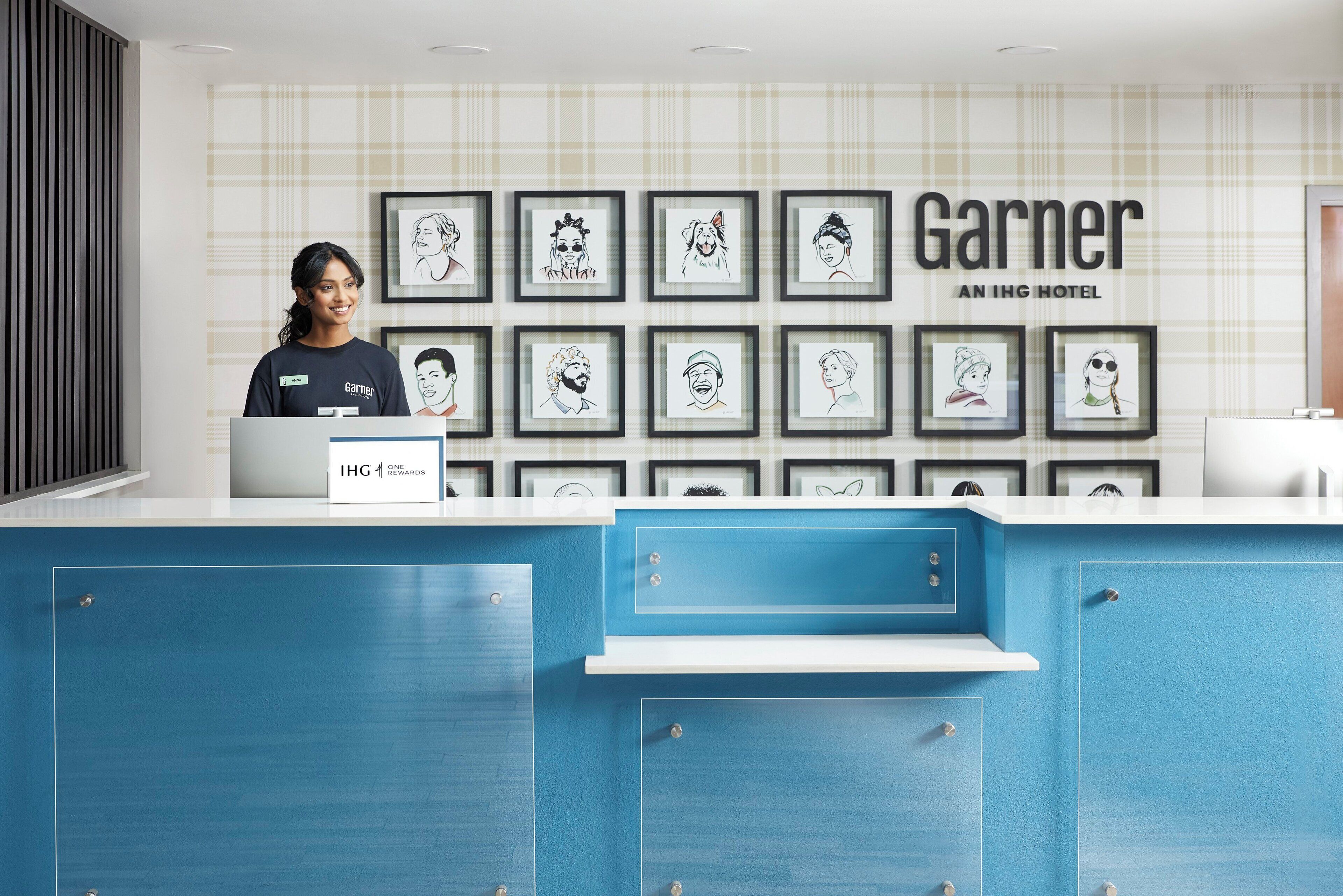 Un mostrador de recepción de hotel con obras de arte enmarcadas en la pared y una barra azul.