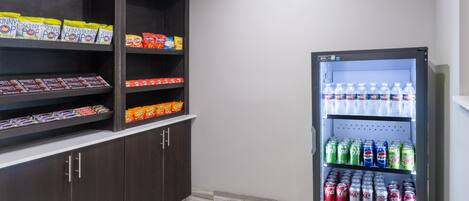 Máquina expendedora llena de aperitivos y bebidas, como papas fritas, caramelos y refrescos.