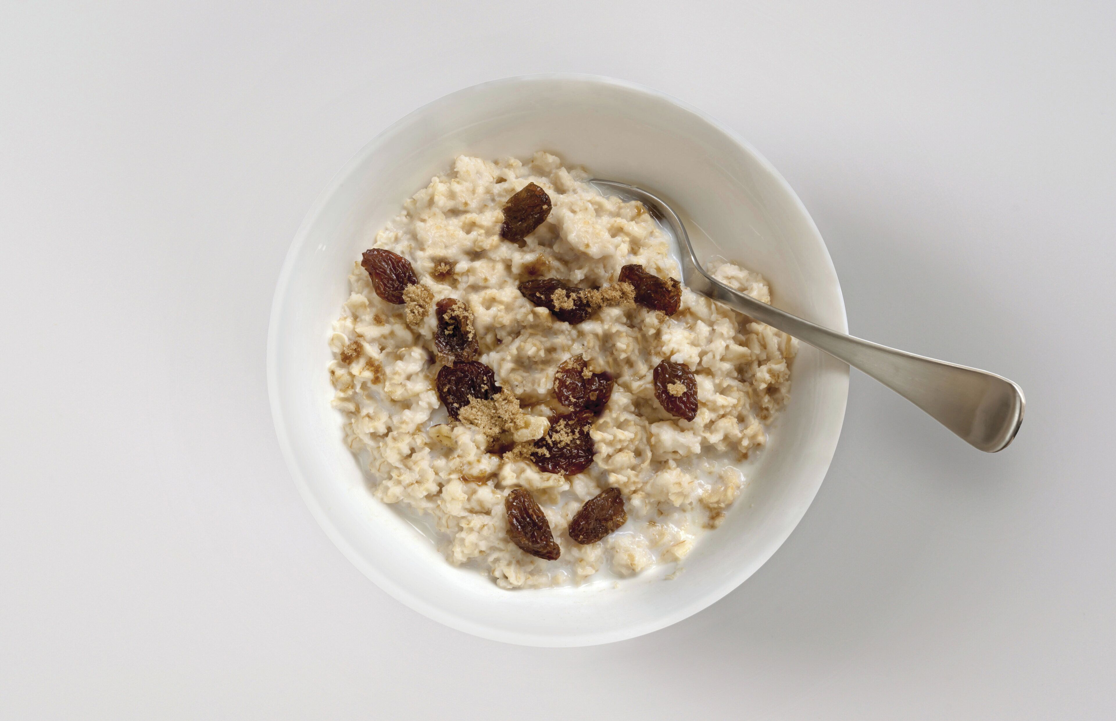 Un tazón de avena con pasas y una cuchara.