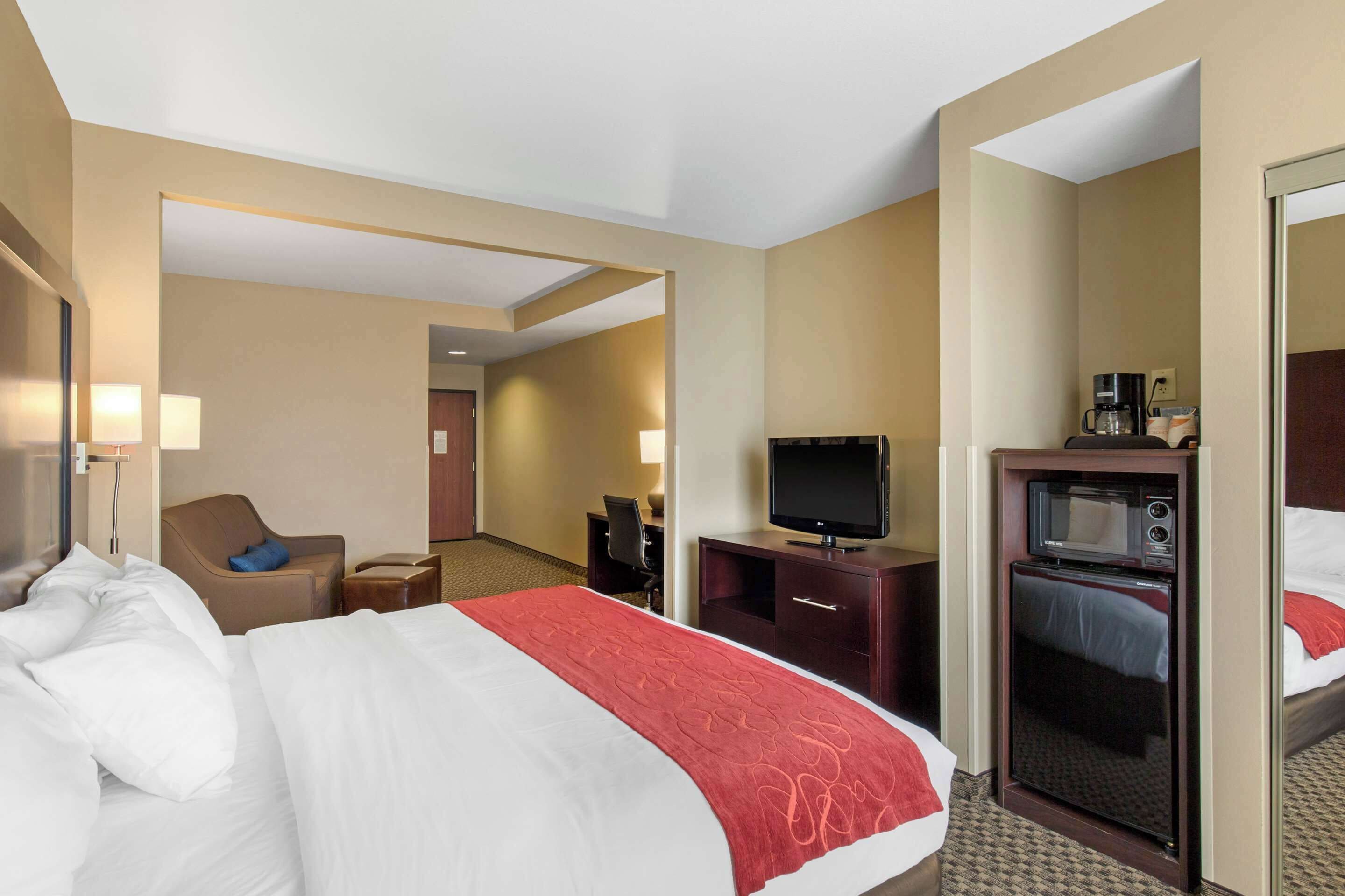 A hotel room with a bed, a television, a microwave, a desk, and a chair.