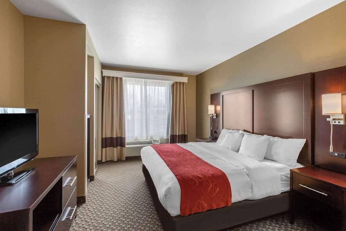 A hotel room with a bed, a television, a desk, and a window with curtains.