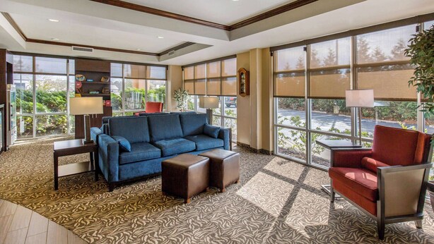 A spacious lobby with a blue sofa, a red armchair, and a patterned carpet. - Comfort Suites Seaford (Seaford)