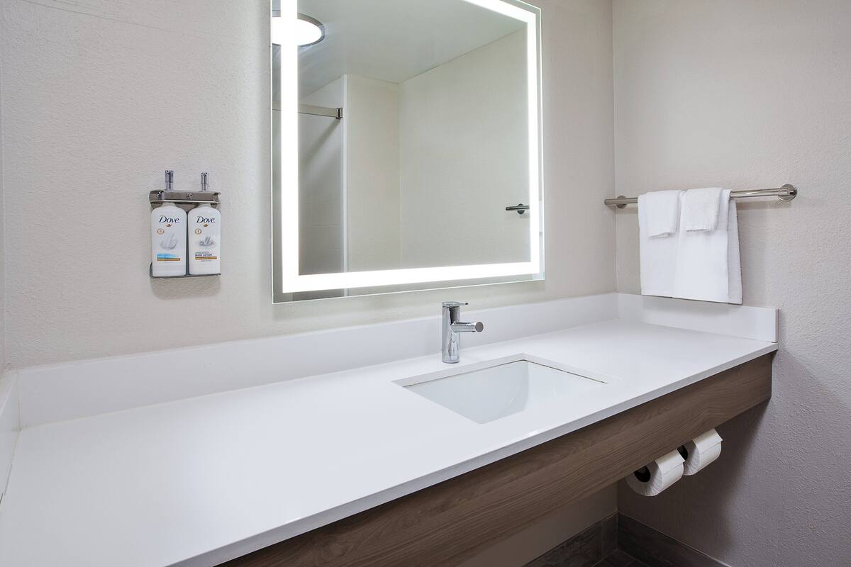 A bathroom with a white sink, a mirror, and a towel rack.
