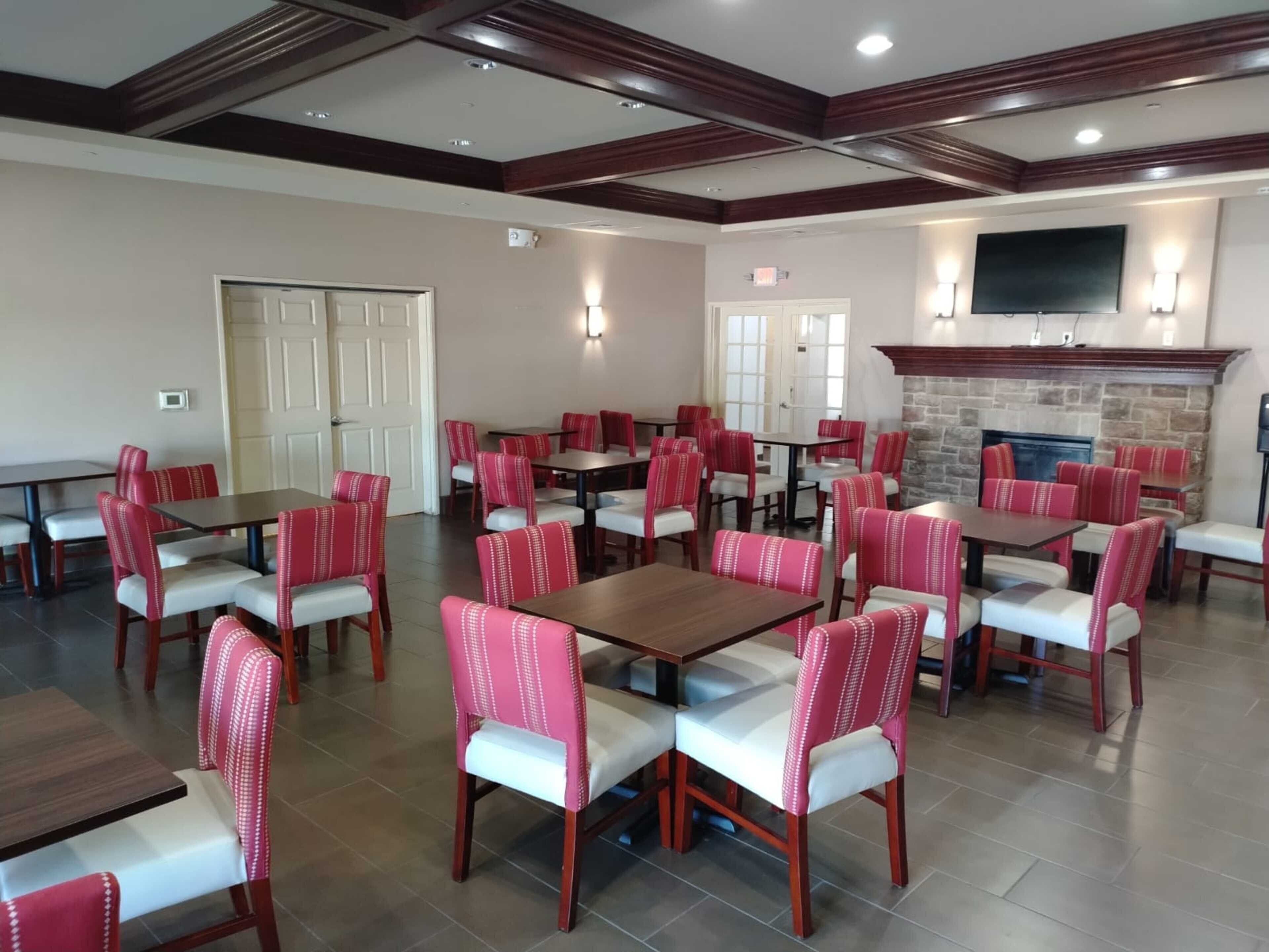 A dining area with multiple tables and chairs, a stone fireplace, and a flat-screen TV mounted on the wall.