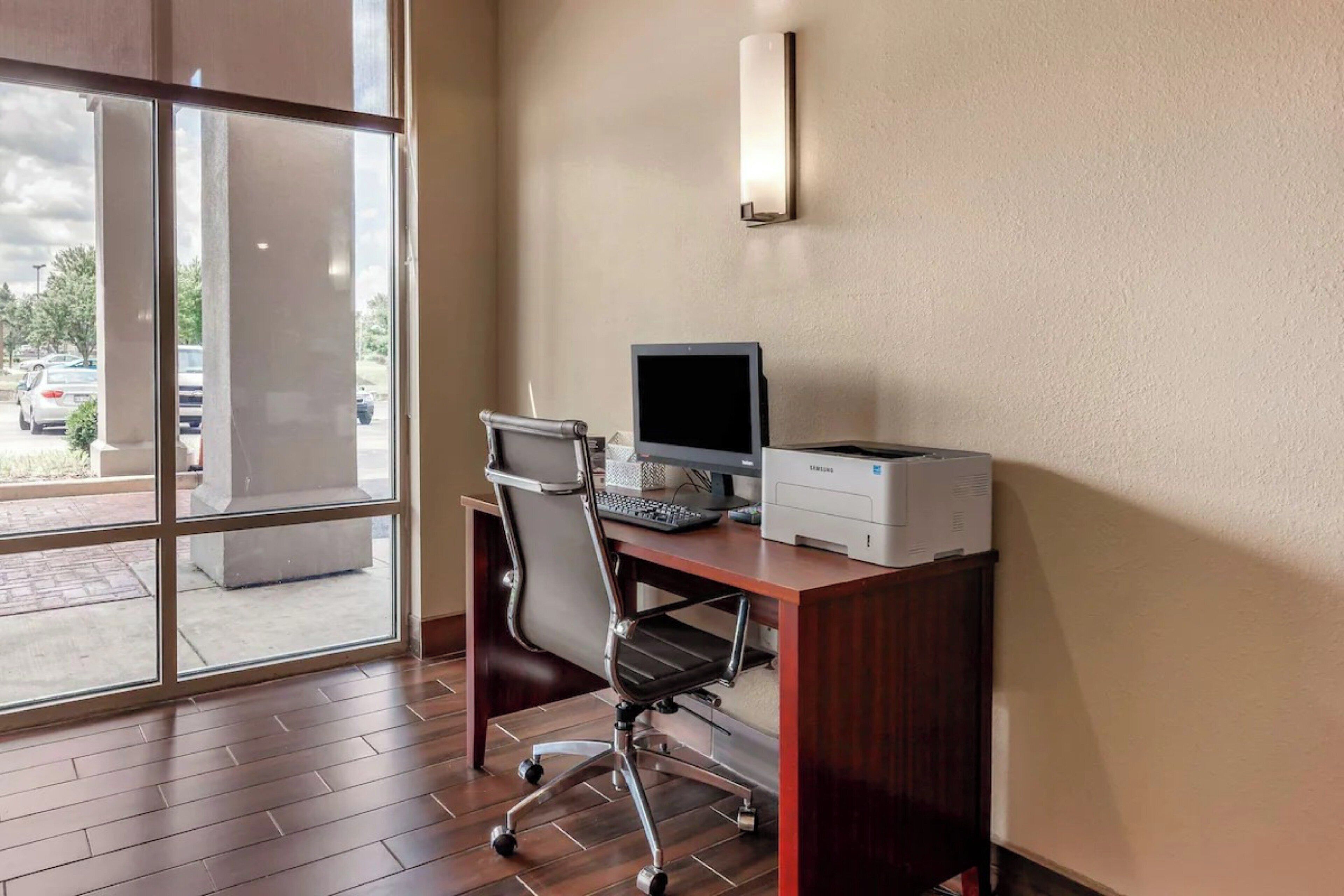Un espace de bureau moderne comprenant un bureau, un ordinateur, une chaise et une imprimante.