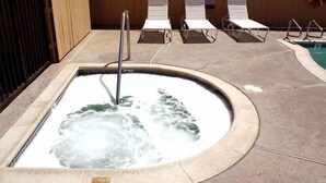 A hot tub with a metal ladder, surrounded by lounge chairs and a pool. - Escondido Lodge (Escondido)