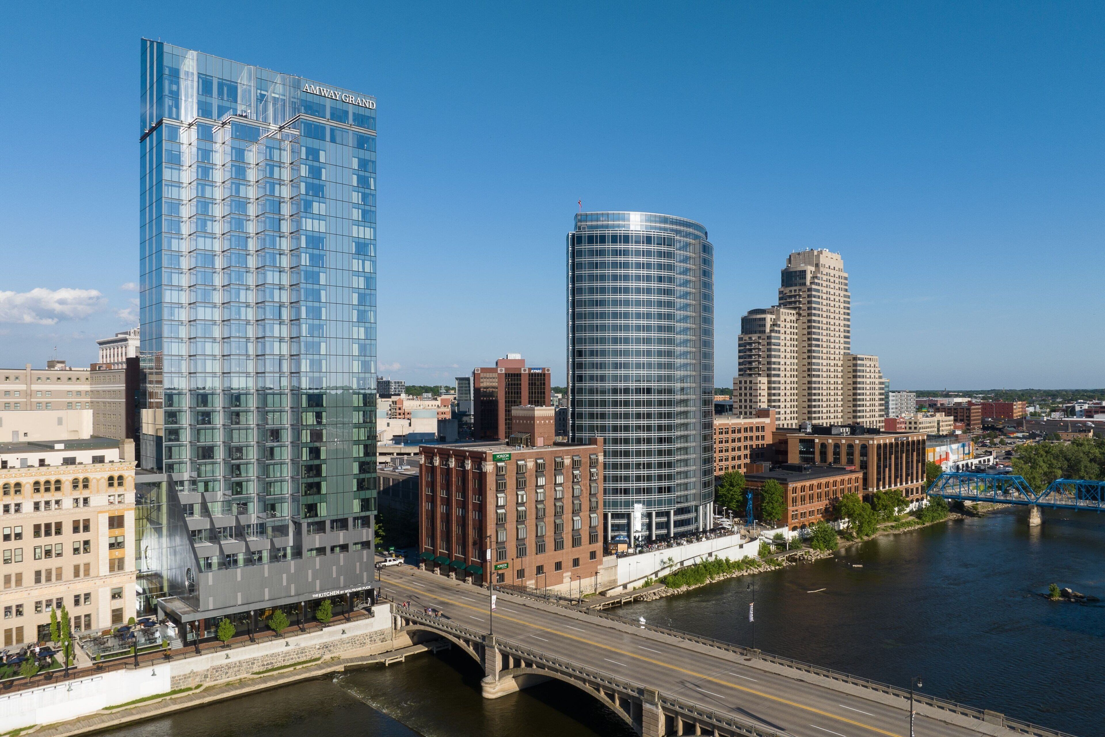 A modern cityscape with a prominent glass building labeled "AMWAY GRAND" and a curved glass structure.