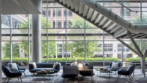 Un salon moderne doté d’un escalier, de grandes fenêtres et de meubles contemporains.