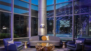 Un espace de détente moderne comprenant un canapé, deux fauteuils, une table basse en verre et un pilier central.