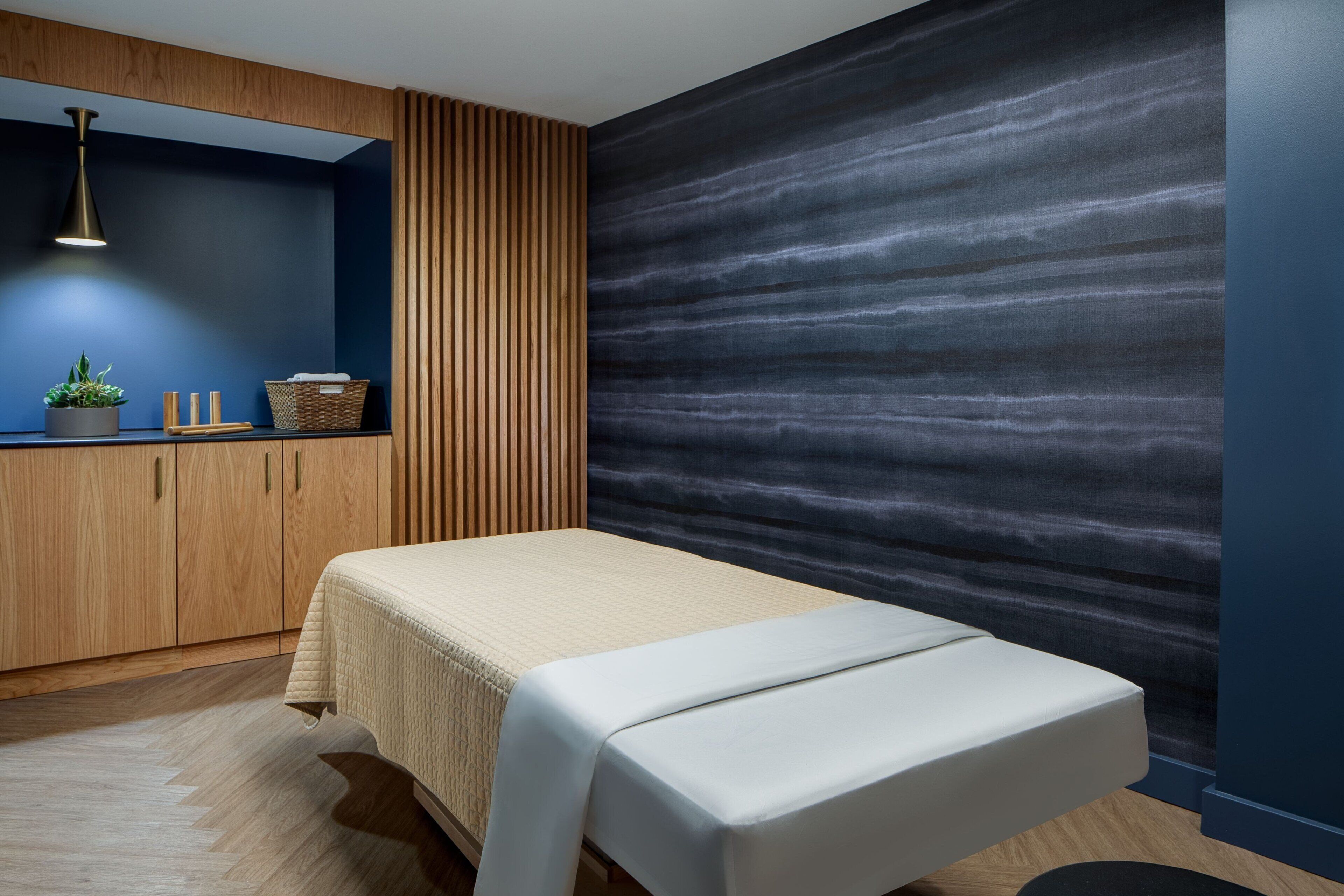 Een moderne kamer met een bed, houten kasten, een wandplank met een plant en een gestructureerde muur.