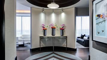 Un hall d’hôtel moderne avec un comptoir d’accueil incurvé, trois vases de fleurs, une grande œuvre d’art encadrée et un canapé en arrière-plan.
