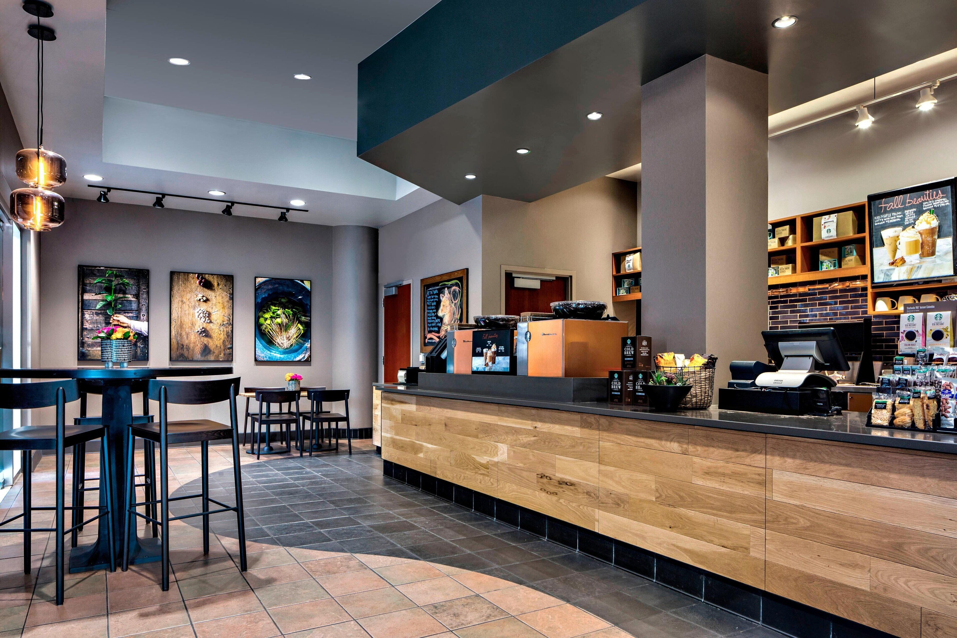 Zona de bar moderna con mostrador de madera, taburetes y un tablero de menú.