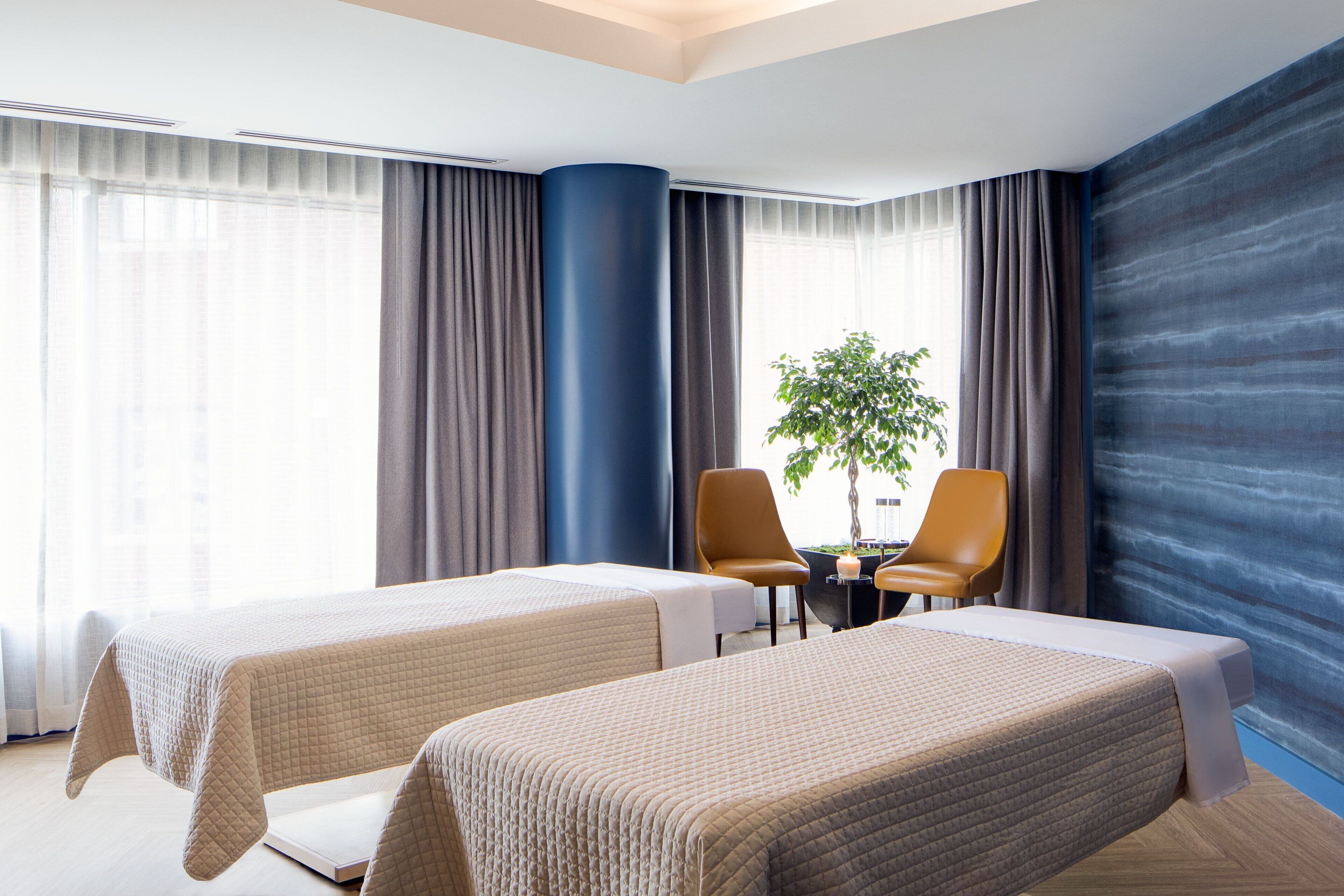 A hotel room with two beds, a desk, and a chair.