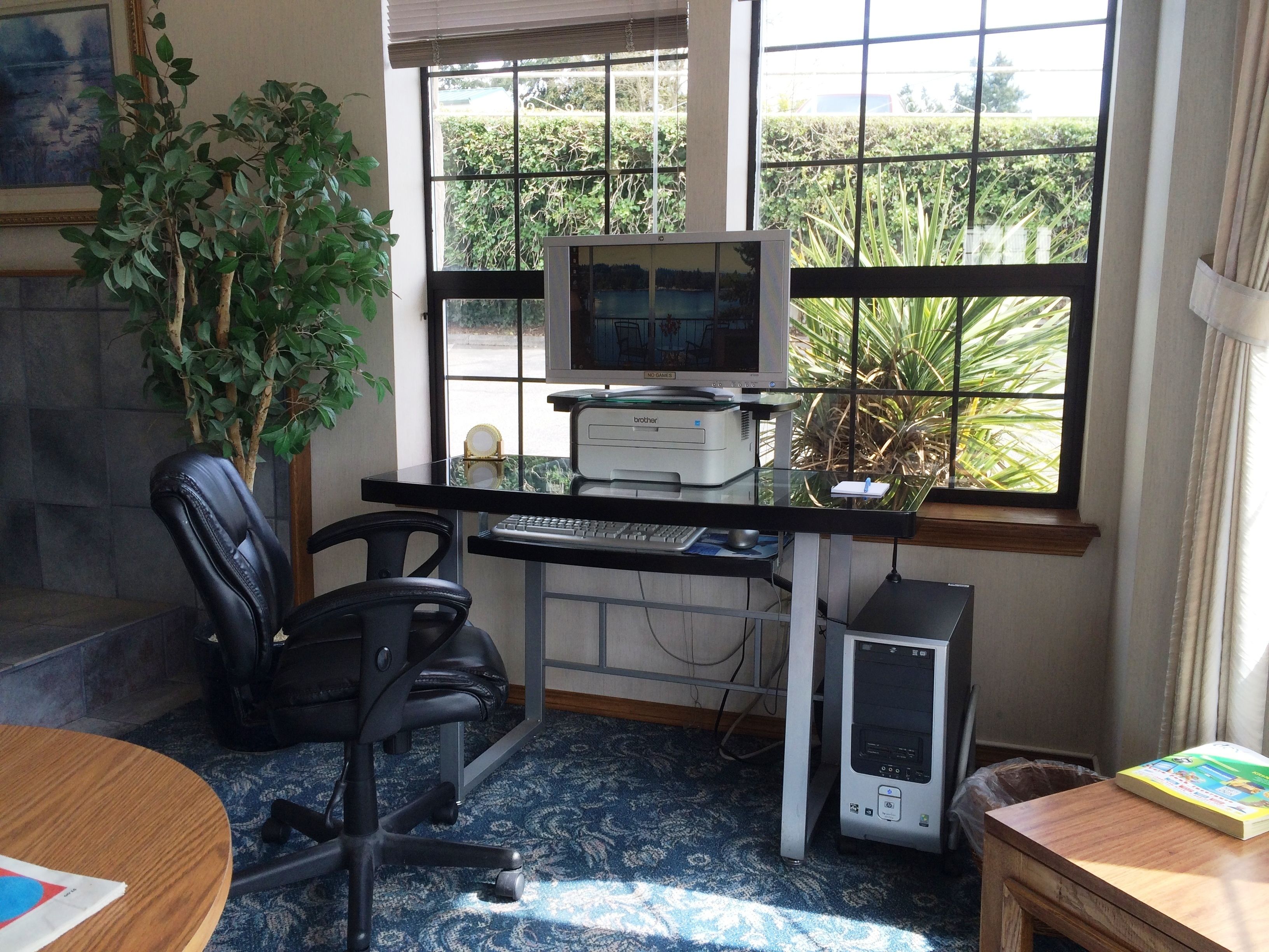 A home office with a computer desk, two chairs, a printer, a desktop computer, and a bookshelf.