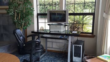 A home office with a computer desk, two chairs, a printer, a desktop computer, and a bookshelf.