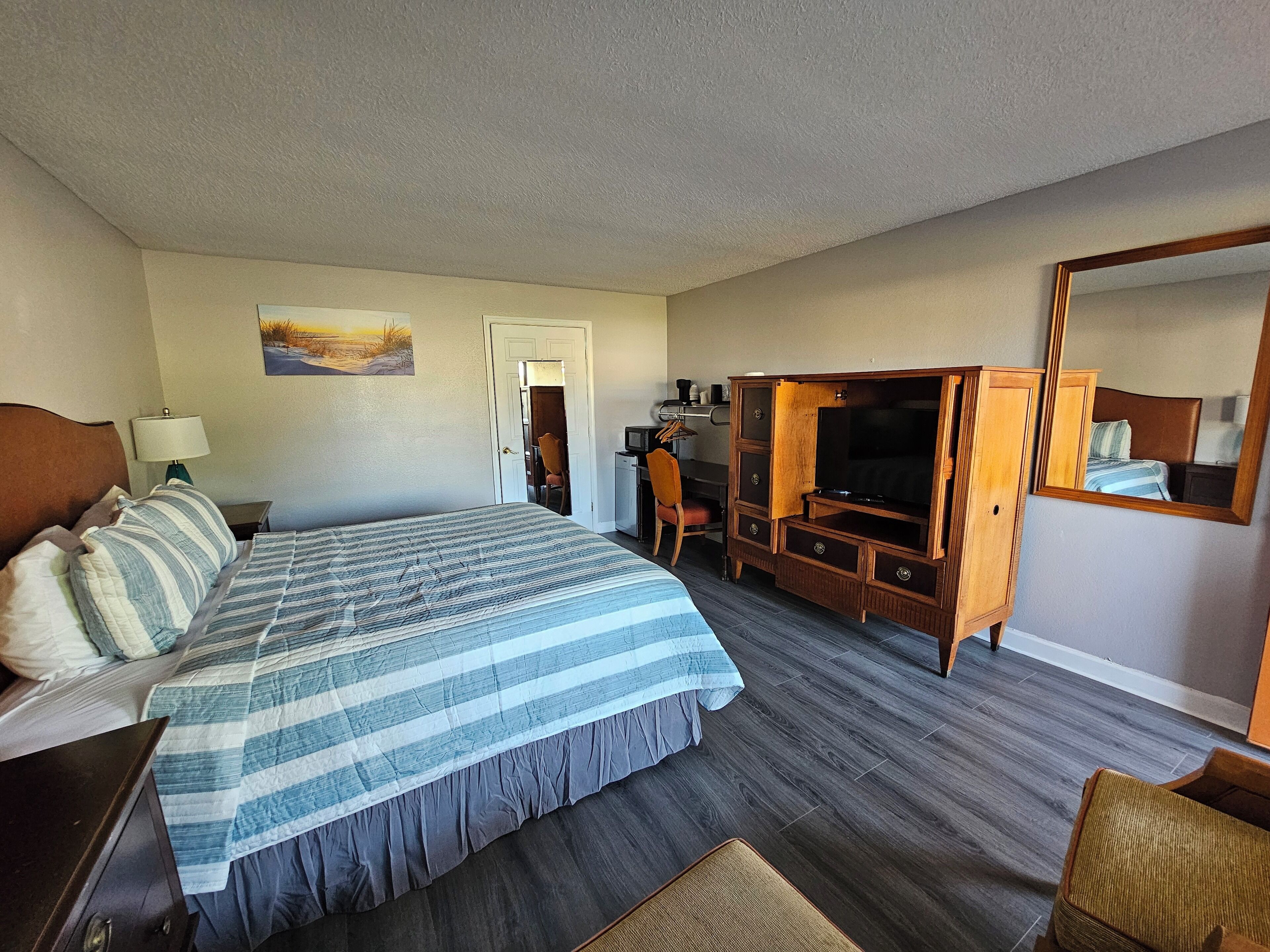 A hotel room with a large bed, a television, a desk, and a chair.